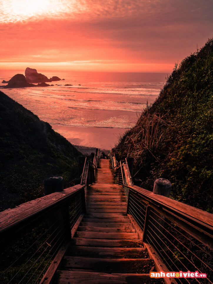 Một cầu thang dài được nối từ trên đồi xuống bãi biển. Khung cảnh này đang chìm đắm trong ánh chiều tà với sắc màu đỏ rực làm bạn muốn thời gian ngừng lại để ngắm nhìn vẽ đẹp này lâu hơn. 