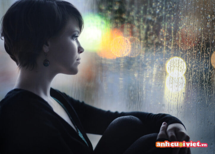 Cô gái ngồi ngắm mưa và suy ngẫm về cuộc đời. 